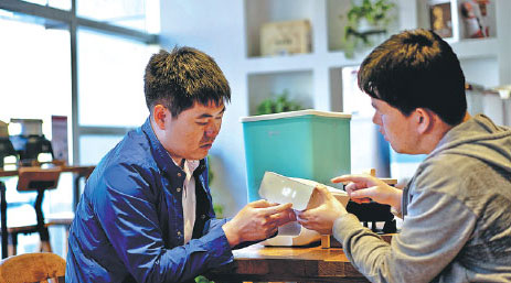 Yang Jian (left) talks with a researcher about how to improve the smart rice storage box, in Shenyang, Liaoning province.Provided To China Daily