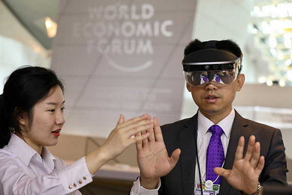 A man experiences augmented reality equipment during the World Economic Forum in Dalian, Liaoning province, June 27. (Photo/China Daily)