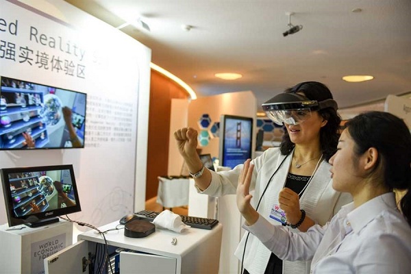 A guest at the Summer Davos tries out head gear at the augmented reality show area during the summit in Dalian yesterday. In a speech, Premier Li Keqiang said China had achieved better-than-expected results in driving mass entrepreneurship and innovation. (Xinhua)