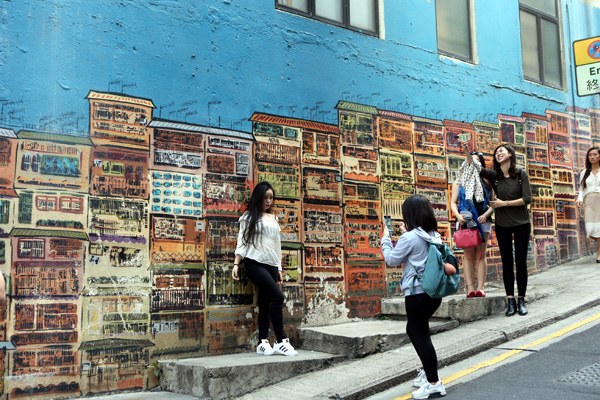 Tourists pose for photos in Hong Kong's main financial district. (Photo by Li Peng/Xinhua)