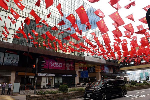 A car drives under Chinese national flags and flags of Hong Kong Special Administrative Region in Tsim Sha Tsui of Hong Kong, China, June 27, 2017. (Photo/Xinhua)