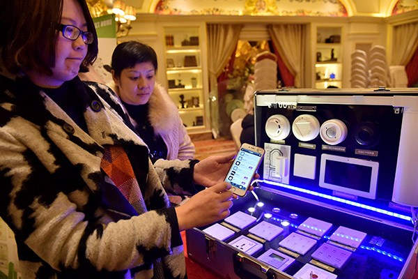 A woman demonstrates how to use an app to manage lights and electronics at home during an IoT expo in Hangzhou, capital of Zhejiang province. (Photo/China Daily)