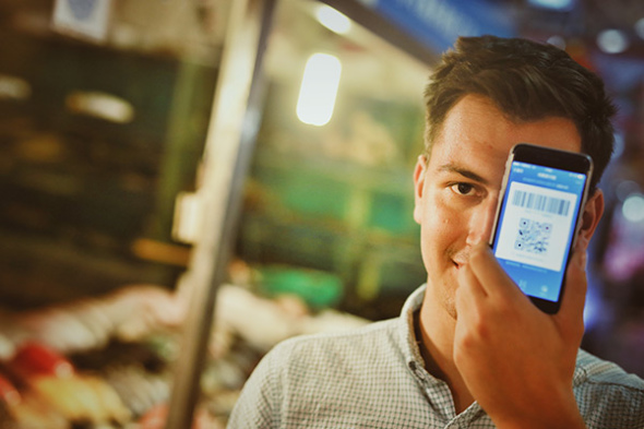 An international student from Romania uses Alipay app on his mobile phone at a store in Beijing. (Photo provided to China Daily)