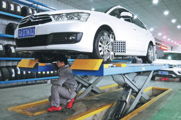 A worker repairs a car at a 4S dealership in Nanjing, Jiangsu province. (Photo by An Xin/For China Daily)
