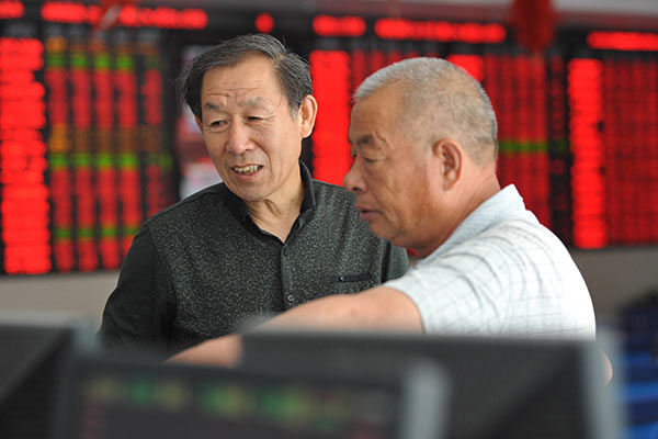 Investors check out stocks at a brokerage in Fuyang, Anhui province. (Photo/China Daily)