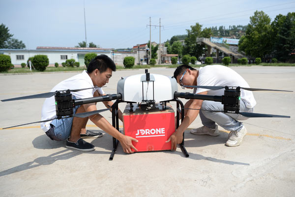 Staff from JD.com Inc attach a package to a drone in Xi'an, capital of Shaanxi province. (Photo/Xinhua)