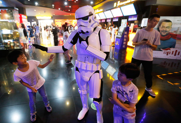 A man dressed up as a robot plays around with two kids at a Wanda cinema in Qingdao, Shandong province. (Photo by He Haier/For China Daily)