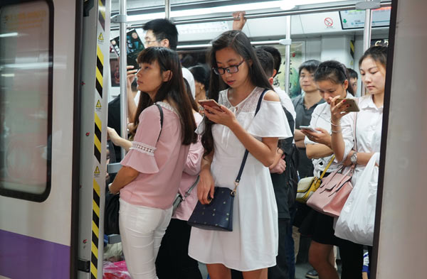 Passengers read e-books on mobile devices on a subway train in Guangzhou, Guangdong province. (Photo by Zhang Yang/For China Daily)
