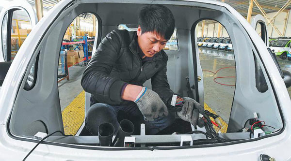 A worker assembles parts in an electric car on a production line in Weifang, Shandong province. (Photo by Ao Tu/For China Daily)