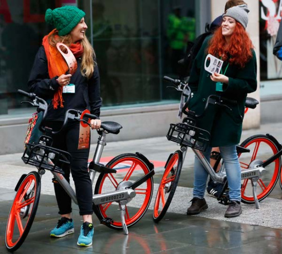 Two women ride Mobikes in Manchester in the United Kingdom. (Photo/Xinhua)