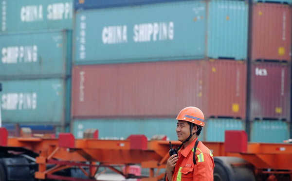 A worker directs the unloading of containers in Qingdao Port, Shandong province. (Photo by Yu Fangping/For China Daily)
