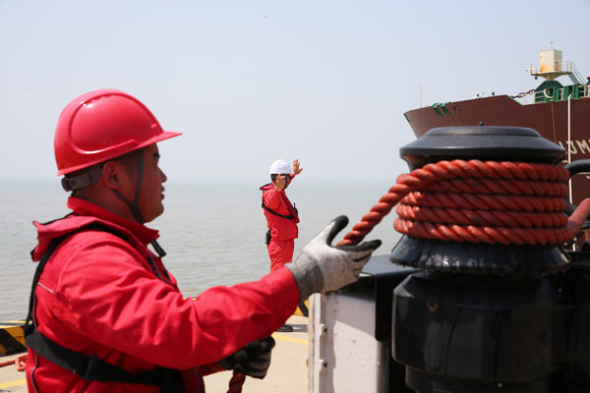 Two workers direct an LNG cargo to shore at Nantong Wharf in Jiangsu province. (Photo by Xu Congjun/For China Daily)