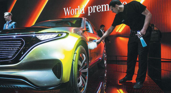 An employee cleans the new Mercedes EQ concept car during the press preview of the Paris Motor Show last year in France. (Photo by Christophe Morin/For China Daily)