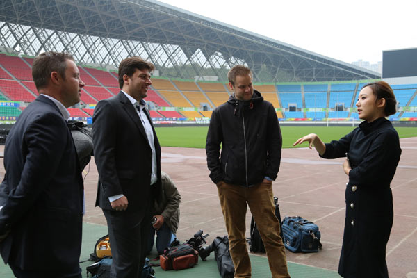 Wen Xiaoting, chairwoman of the soccer club Guizhou Hengfeng Zhicheng, explains her brand promotion idea during chat with three German Channel 2 television staff in a soccer stadium in Guizhou province. (Photo by Yang Jun/For China Daily)