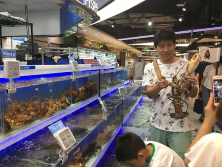 A customer has a picture taken with a lobster at the Hema store in Chaoyang, Beijing on Thursday. (Photo: Dong Feng/GT)