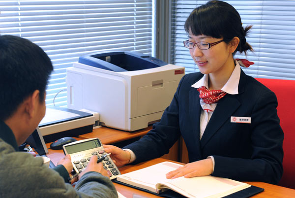 An employee from the Bank of China introduces financial services to a client in Zhengzhou, Henan province. (Photo by Sha Lang/For China Daily)