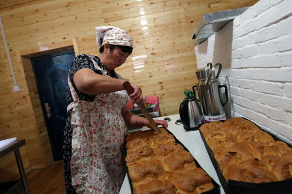 A woman prepares food for Russian tourists in a folk village in Inner Mongolia. (Photo by Wang Zhuangfei/For China Daily)