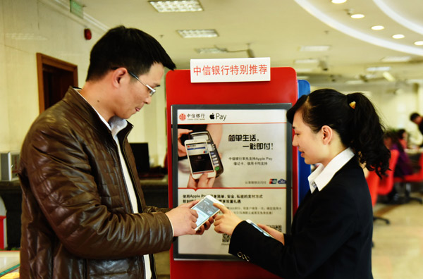 A man learns how to use Apple Pay at a bank in Hangzhou, capital of Zhejiang province. (Photo by Long Wei/For China Daily)