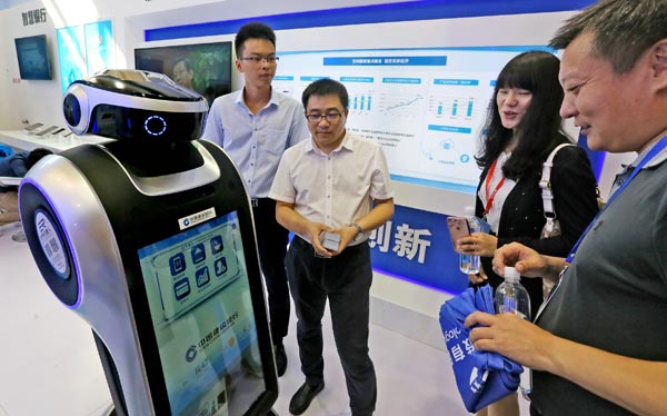 A service robot rolled out by China Construction Bank interacts with visitors at a financial fair in Beijing. (Photo by Lei Kesi/For China Daily)