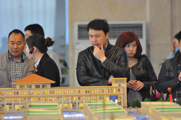 A man inspects a property model display in Rizhao, Shandong province, on Jun 14, 2014 . (Photo provided to China Daily)