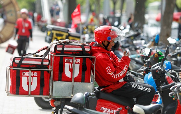 A Baidu Waimai delivery worker receives online food orders on his phone in a street in Beijing. (A QING / FOR CHINA DAILY)