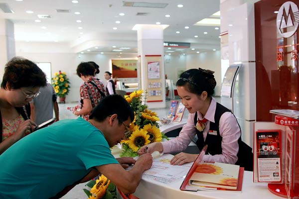 Customers fill out forms at a branch of China Merchants Bank in Haikou, Hainan province. (Photo by Zhang Mao/China Daily)