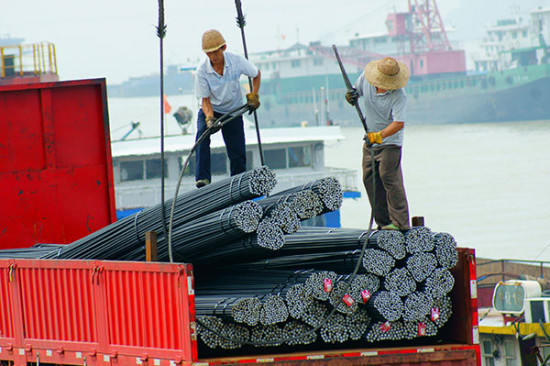 Workers load steel products at a logistics park in Yichang, Hubei province. [Photo/China Daily]