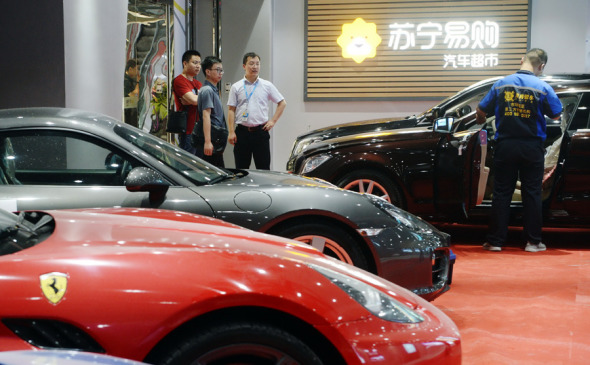 Technicians at Suning Auto Supermarket in Nanjing, Jiangsu province, explain the features of new models of different brands of cars to prospective customers.(Photo: Cui Xiao/For China Daily)