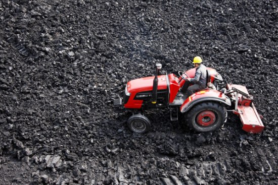 A man operates a tractor to crush coal, one of the fuels used by the thermal power industry, in Huaibei, Anhui province. [Photo by WU HE/CHINA DAILY]