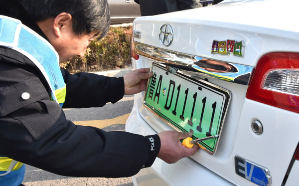 An employee of the Jinan vehicle administration department installs a plate on an electric car in Jinan, Shandong province, Dec 1, 2016. (Photo for China Daily)