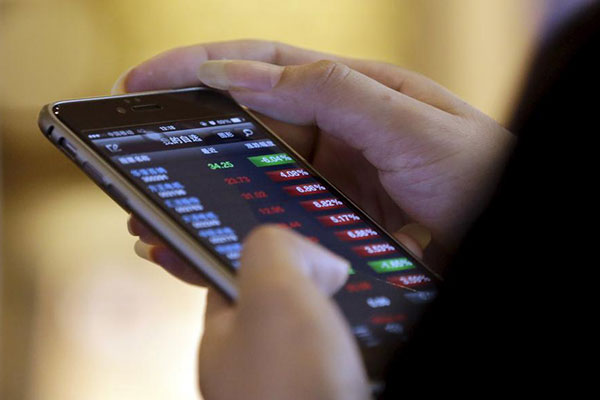 A man checks share prices on his mobile phone while waiting for his coffee at a Starbucks branch in Beijing July 16, 2015.(Photo/Agencies)