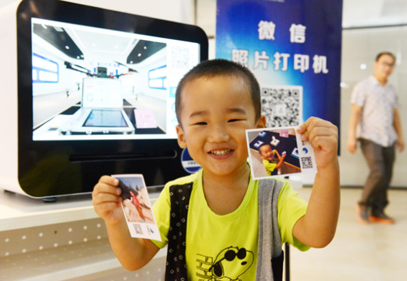 A boy is impressed with the images produced by a WeChat photo printer.