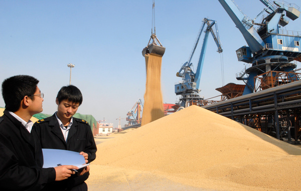 Two officials from Shandong Inspection and Quarantine Bureau check imported soybeans at Rizhao port, Shandong province. (Zhu Yuanli/for China Daily)