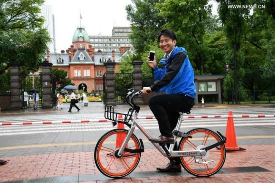 A TV reporter tries out a shared bicycle in Sapporo, Japan, on Aug. 22, 2017. (Photo: Xinhua/Hua Yi)