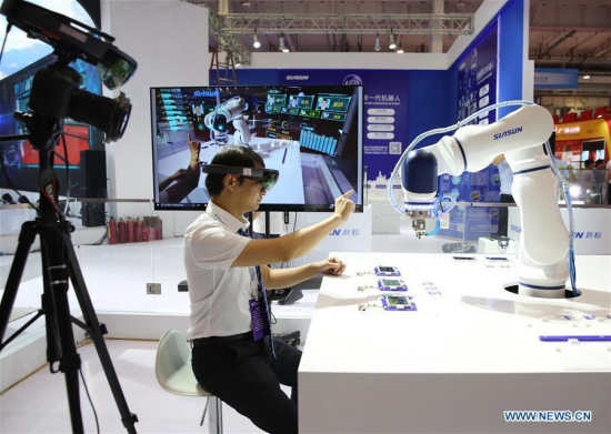 A staff member demonstrates a robot during the media preview of 2017 World Robot Conference at Beijing Yichuang International Conference and Exhibition Center, in Beijing, capital of China, Aug. 22, 2017. The conference will be held from Aug. 23 to Aug. 27, consisting of forum, exposition and robot competition. (Xinhua/Jin Liwang)