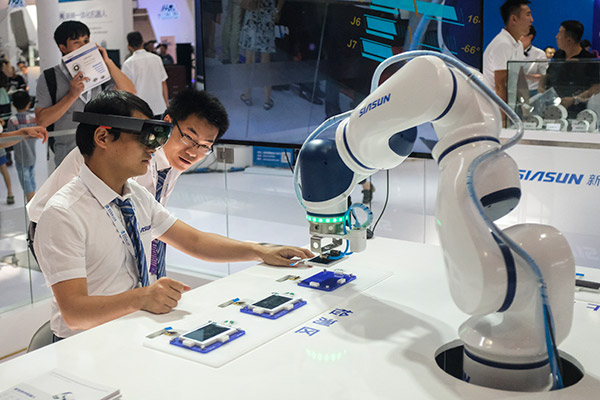 Employees of Siasun Robot & Automation Co use a robot and special eye gear to demonstrate phone repairs during the World Robot Conference held in Beijing, Aug 23, 2017. (Photo/China Daily by Akash Ghai)