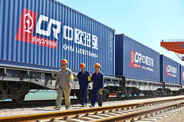 Workers walk along a Europe-bound freight train on Aug 24 in Yiwu, East China's Zhejiang province. (Photo/China Daily by Zhu Xingxin)