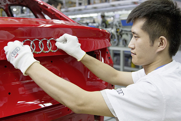 A worker checks up the logo of a car at one of Audi's production lines. (Photo provided to China Daily)