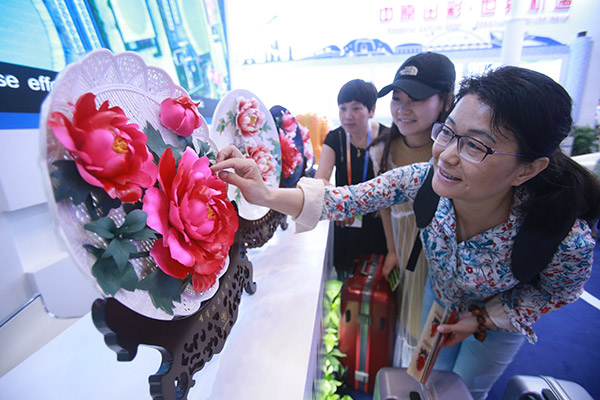 Visitors examine porcelain products made in Luoyang, Henan province, during an international fair for trade in services held in Beijing. (Chen Xiaogen/for China Daily)