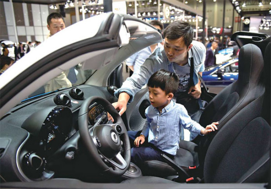A visitor and his child try out a new car at an auto show in Wuhan, Hubei province. (Photo/Xinhua)