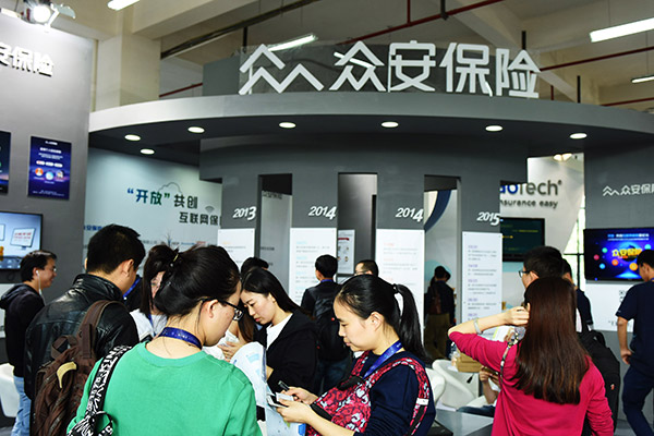 Visitors pass the exhibition stand of ZhongAn Online Property and Casualty Insurance Co Ltd in Hangzhou. (Long Wei/for China Daily)