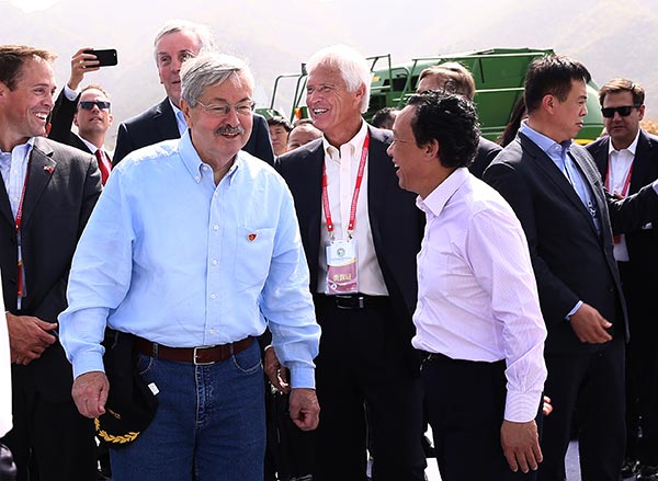 U.S. Ambassador Terry Branstad, front left, and Qu Dongyu, front right, vice-minister of agriculture, react as U.S. farmer Rick Kimberley witnesses, back center, during the launch ceremony of China-U.S. Friendship Demonstration Farm in Luanping county, North China's Hebei province, on Sept 23, 2017. ZOU HONG / CHINA DAILY