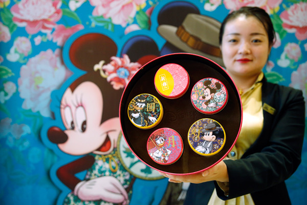 A worker displays Disney-themed mooncakes at a store in Shanghai earlier this month. Tang Yanjun/China News Service