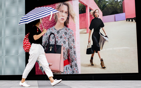 A woman walks past a Louis Vuitton advertisement in Fuzhou, capital of Fujian province. (Photo by Chen Hao/For China Daily)