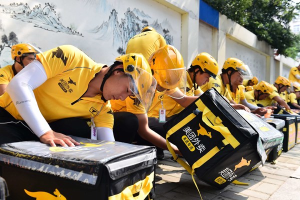 Couriers of an online food delivery company check the delivery boxes. Photo/Xinhua