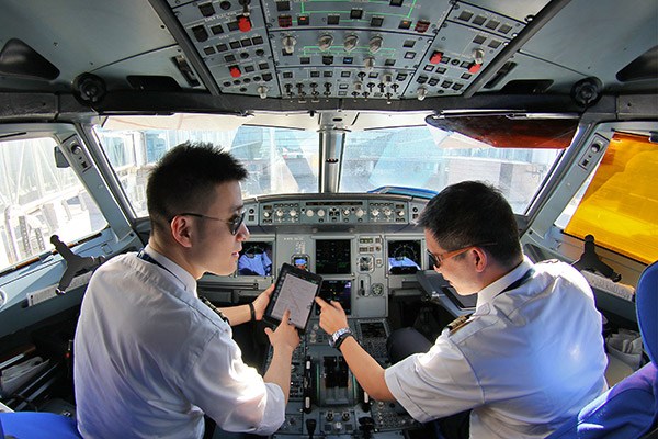 An aircraft commander of China Eastern Air Holding Co discusses the flight plan with his co-pilot in the plane. (Tang Ke/for China Daily)