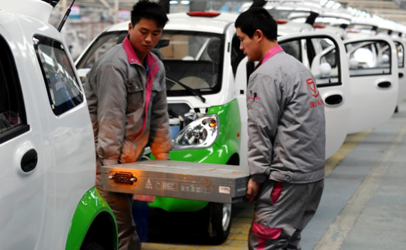 Workers carry an electric car battery at the production line of an e-carmaker in Zhejiang province. (Photo provided to China Daily)