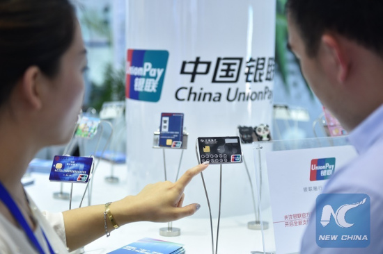 A staff member (L) of China UnionPay introduces a new type of bank card with visualized information function at an exhibition in Beijing, capital of China, June 1, 2015. (Xinhua/Li Xin)