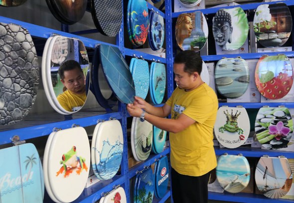 A man examines a toilet seat in a factory in Anshun, Guizhou province, which makes colorful seats with artistic designs. (Photo by Yang Jun/China Daily)