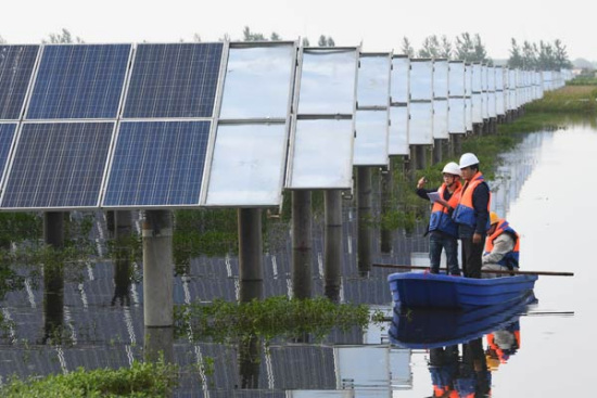 Workers check solar power generation facilities in Tianchang, East China's Anhui province. [Photo by Song Weixing/For China Daily]